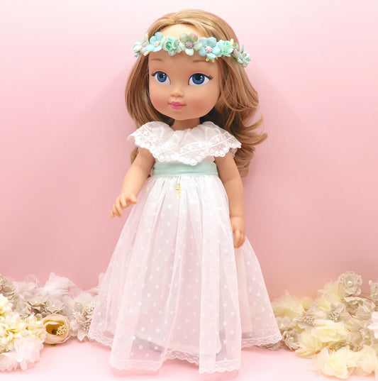 Muñeca de comunión personalizada como tú con vestido de tul de plumeti sin mangas y volante en escote bordado. Puedes personalizar el modelo de muñeca, el color del fajín, las flores y los zapatos. Sólo en My little twin
