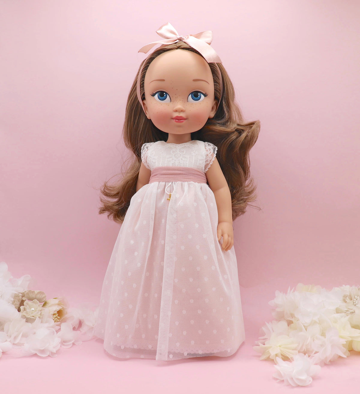 Muñeca de comunión personalizada como tú con vestido Nicole con falda rosa, de tul de plumeti con pecho y mangas de encaje. Puedes personalizar el modelo de muñeca, el color del fajín, las flores y los zapatos. Sólo en My little twin.