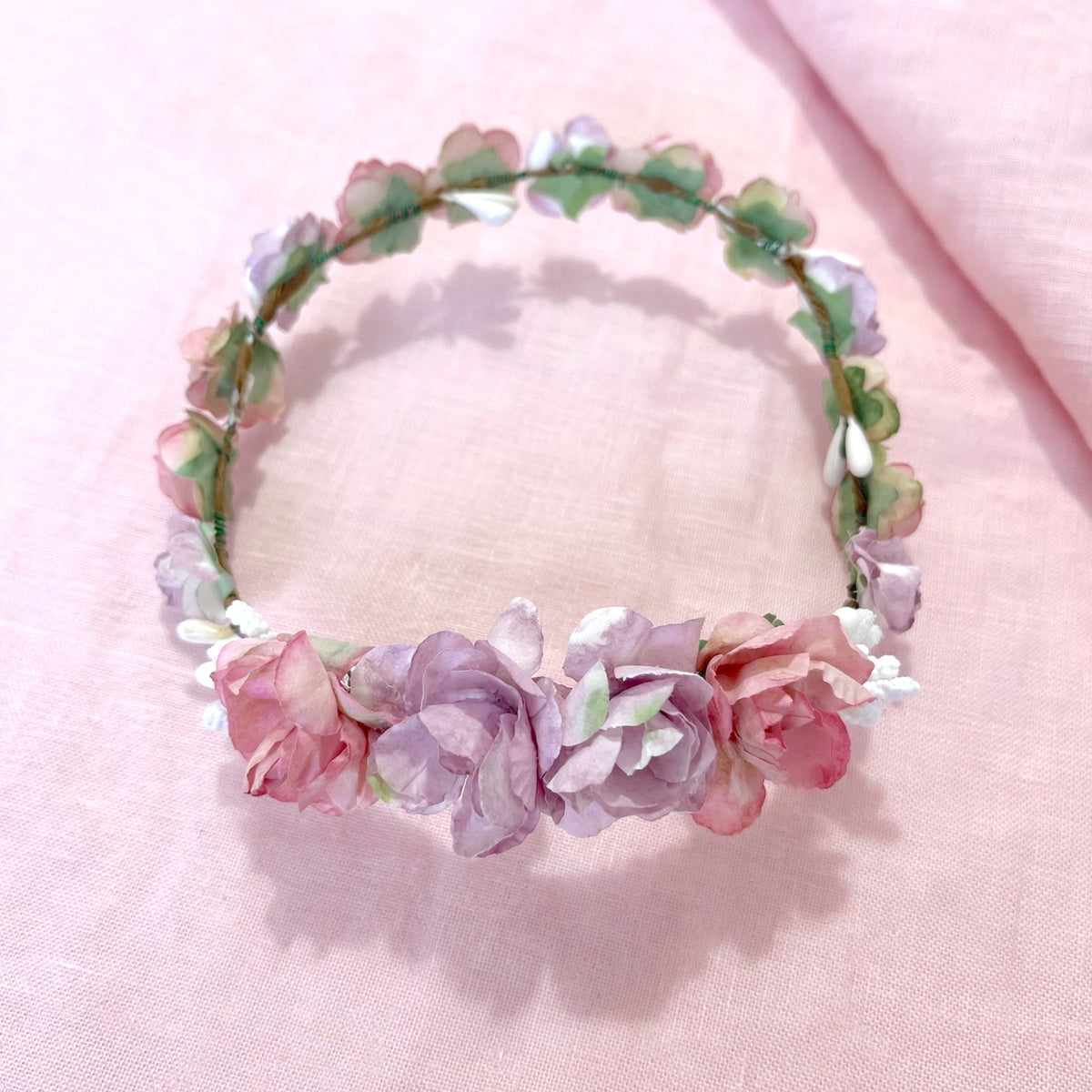 Coronita de flores Amelie para muñecas de comunión My little twin en tonos rosas y morados. Elige la más parecida a la niña y acompáñala con un bonito peinado. Se puede colocar con las flores grandes hacia delante o hacia atrás.
